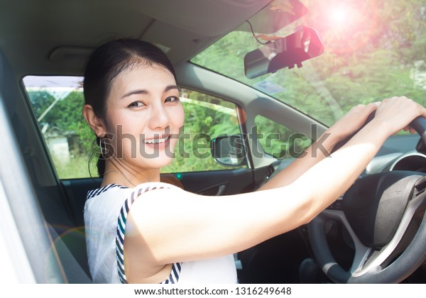 Asian woman driving car, sunny day. UV protection\
or skin care concept