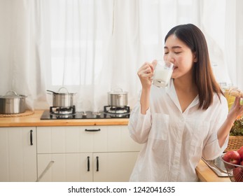 asian woman eating bread and drink milk  in the kitchen