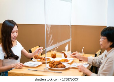 Asian woman eating food while siting separate and keep distance with table plastic shield partition in restaurant, new normal, restaurant, coronavirus outbreak and social distancing concept - Shutterstock ID 1758760034