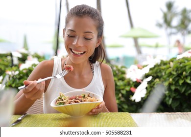 Asian Woman Eating A Fresh Raw Tuna Dish, Hawaiian Local Food Poke Bowl, At Outdoor Restaurant Table During Summer Travel Vacation. Hawaii Poke Bowl Food Plate. Ahi Tuna Hawaiian Cuisine.