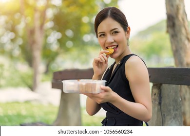 Asian Woman Eating Healthy Peanut Butter Sandwich Cracker Sitting At Park, Appetizer Lunch Box.