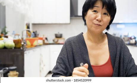 Asian Woman Eating Ice Cream Funny At Home. Smiling