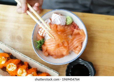 Asian Woman Eating Salmon Slice Sashimi With Rice In Japanese Restaurant