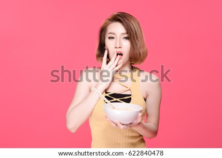 Asian woman eating spicy instant noodle, beauty face natural makeup, isolated over pink background.