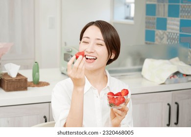 Asian woman eating strawberries in dining room