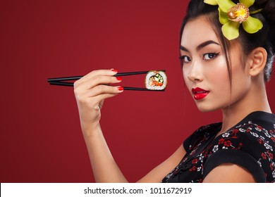 Asian woman eating sushi and rolls on a red background. International Women's Day, Black Friday, Setsubun Japanese Festival, sushi sale.