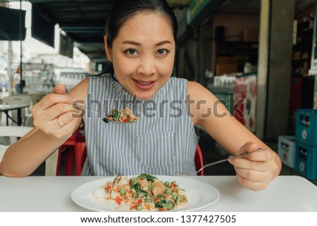 Asian woman is eating Thai rice stir-fried pork and basil.