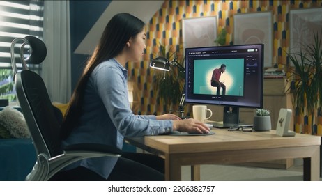 Asian Woman Editing Photo In Photoshop For Customer On Personal Computer While Sitting At The Table At Home Office And Working Remotely