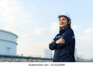 Asian Woman Engineer Arm Crossed And Smile With Confident Looking Forward To Future With Oil Refinery Plant Factory In Background. 