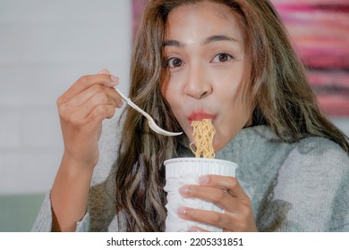 Asian Woman Enjoy Eating Hot Instant Noodles Alone In The Living Room After House Work. Young Freelance Female Work From Home.