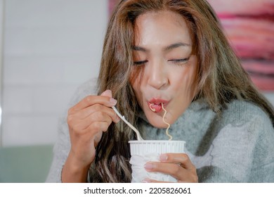 Asian Woman Enjoy Eating Hot Instant Noodles Alone In The Living Room After House Work. Young Freelance Female Work From Home.