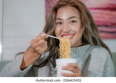 Asian Woman Enjoy Eating Hot Instant Noodles Alone In The Living Room After House Work. Young Freelance Female Work From Home.