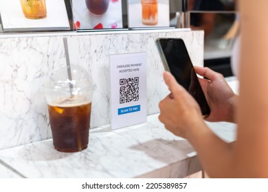 Asian Woman Enjoy Shopping  At Street Market On Summer Holiday Vacation. Attractive Girl Using Mobile Phone Scan QR Code On Bar Counter Making Online Payment Buying Iced Coffee At Outdoor Coffee Shop.