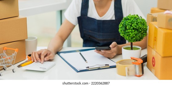 Asian Woman, Entrepreneur, Small Business, SME, Independent, Press The Calculator To Account For Customers Who Order. And Check The Purchase Order Invoice Prepare Parcels For Delivery.