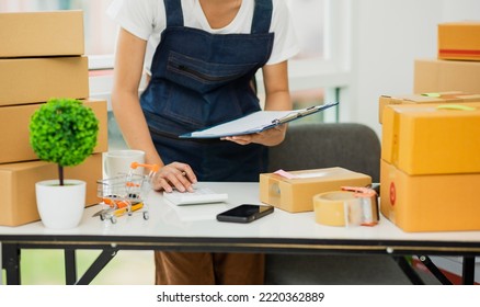 Asian Woman, Entrepreneur, Small Business, SME, Independent, Press The Calculator To Account For Customers Who Order. And Check The Purchase Order Invoice Prepare Parcels For Delivery.