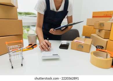 Asian Woman, Entrepreneur, Small Business, SME, Independent, Press The Calculator To Account For Customers Who Order. And Check The Purchase Order Invoice Prepare Parcels For Delivery.