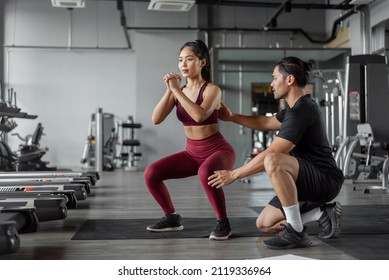 Asian woman exercise with personal trainer in gym. Young healthy woman workout in fitnees with personal coach. Exercises and fitness concept.