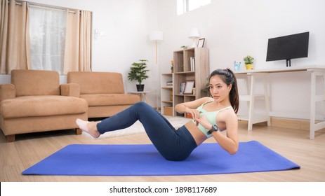 Asian woman exercising at home, she is doing a Russian twist.