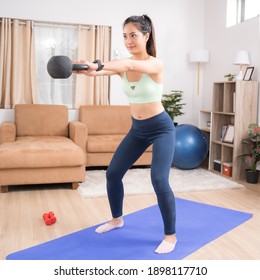 Asian Woman Exercising At Home Using Pendulum Squats