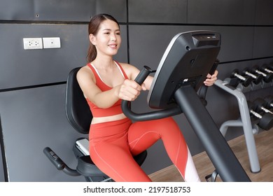 Asian Woman Exercising On Exercise Bike In Fitness Health Care Concept.