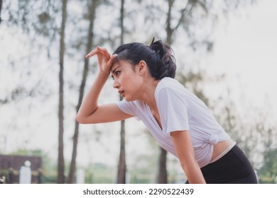 An Asian woman is exhausted and wipe sweat after running, jogger, work out or do morning exercising. Concept of city lifestyle, healthy sport, tired and breathing, refreshment and sweaty. - Powered by Shutterstock