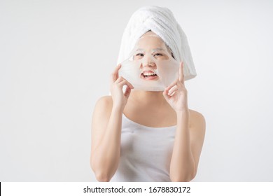 Asian Woman Is Facial Mask Sheet . She Is Happy And Surprise.