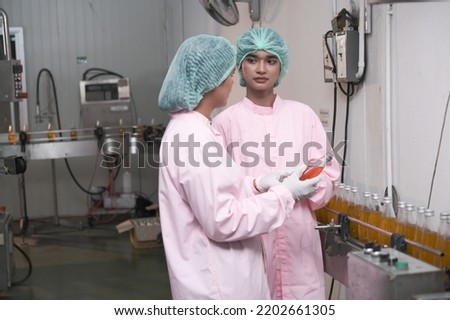 Asian woman factory worker or woman expert quality staff is checking bottles line for beverage