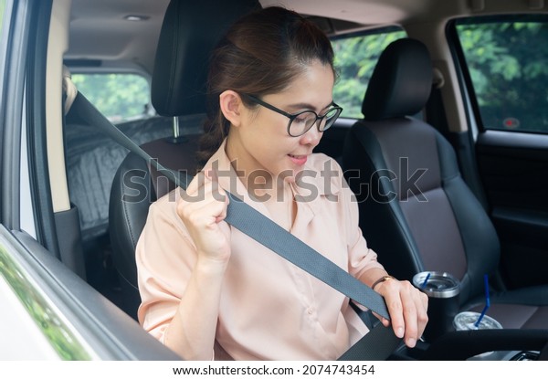 Asian woman fasten the seat belt before driving\
a car. Seat belts are as important as other car safety equipment\
for defense against harmful\
movement.