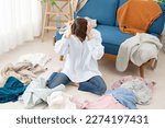 Asian woman feel stress surrounded by clothes at home