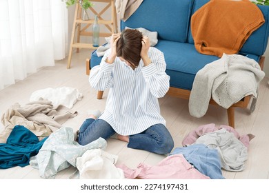 Asian woman feel stress surrounded by clothes at home - Shutterstock ID 2274197431