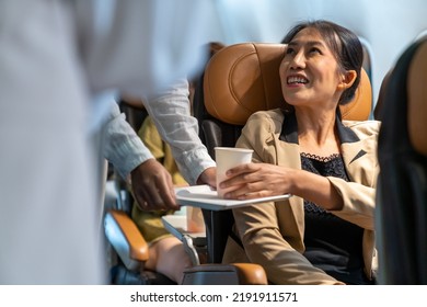  Asian Woman Flight Attendant Walking On Airplane Aisle Serving Food And Drink To Passenger In Airplane. Cabin Crew Working On Duty In Aircraft. Airline Service Business And Travel Vacation Concept.