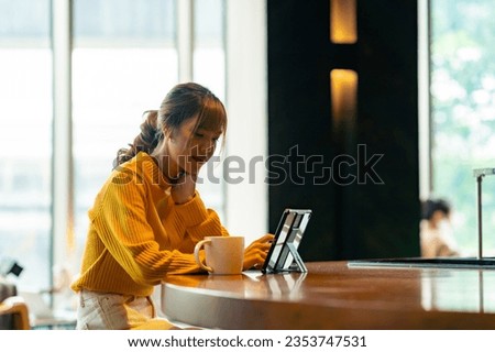 Asian woman freelancer sitting in cafe working corporate business freelance job on laptop computer and digital tablet. Digital nomad people working from anywhere on gadget device and online network.