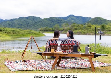 Asian Woman Friends Drinking Coffee Together While Having Breakfast By The Lake At The Camp In The Morning. Attractive Girl Enjoy Outdoor Lifestyle Camping In Forest Mountain On Summer Travel Vacation