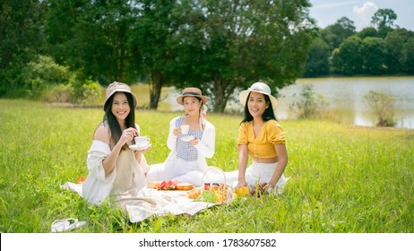 Asian Woman Friends. They Are Having A Picnic, Eating In The Morning.They Drink Coffee.