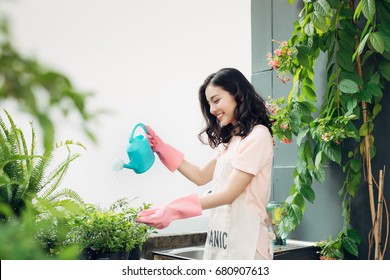 Asian Woman Gardener Watering The Flowers In Her Garden In Summer