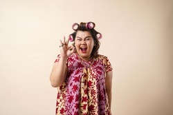 An Asian Woman Gesturing Okay Sign Using Her Hand. Isolated On Cream Background. 