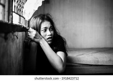 Asian woman get scared human trafficking and trying escape from room but detainees woman stick to handcuffs and detain in dirty room. She was kidnapped or abducted, typically to obtain ransom. - Shutterstock ID 1918423712