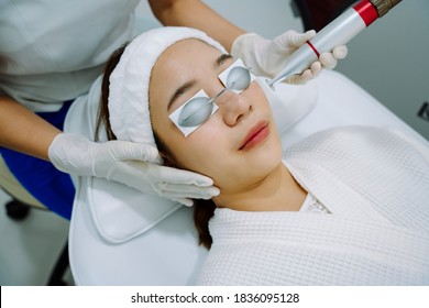 Asian Woman Getting Laser And Ultrasound Face Treatment In Medical Spa Center.