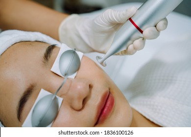 Asian Woman Getting Laser And Ultrasound Face Treatment In Medical Spa Center.