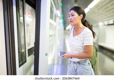 Asian Woman Getting On Train That Just Arrived To Subway Station.