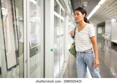 Asian Woman Getting On Train That Just Arrived To Subway Station.