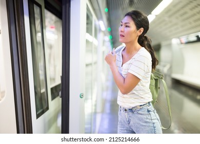 Asian Woman Getting On Train That Just Arrived To Subway Station.