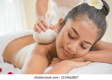 Asian woman getting thai herbal compress massage in spa.