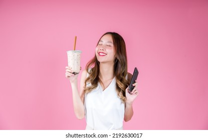 Asian woman girl drinking bubble milk tea excited emotion and holding smart phone, Food and drink delivery concept on the pink background