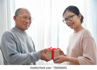 Asian woman giving a brown gift box to elderly man for Birthday, Christmas and New year on white background. - Powered by Shutterstock