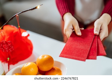 Asian Woman giving red envelope for Lunar New Year celebrations. Hand hold red packet. - Shutterstock ID 2246767821