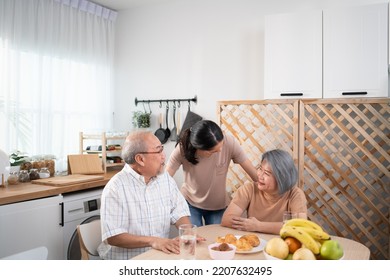 Asian Woman Greeting Father And Mother At Breakfast Table In The Morning At Home. Happy Senior Couple Talking With Daughter. Happy Family Sharing Love Together