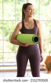 Asian Woman In Group Class Exercise Yoga At Gym. Cheerful Lady Holding Yoga Mat Prepare To Doing Yoka At Home On Green Nature Background.