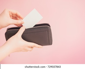 asian woman hand hold and bring out card in her blue purse with pink pastel background