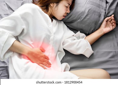 Asian Woman Hand Holding Her Right Side Of Stomach Suffering From Abdominal Pain Laying Down On Bed